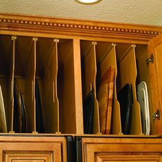 an open cabinet filled with lots of knives and cutting boards in it's drawers