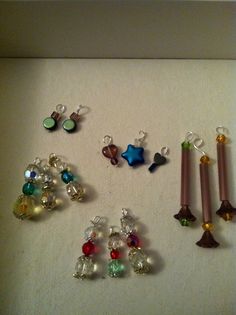 several different colored beads and charms on a white surface next to two candles with one candle in the middle