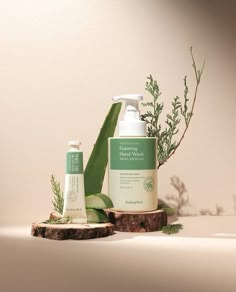 two bottles of body wash sitting on top of a tree stump next to a plant