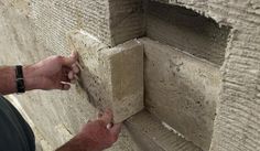 a man that is standing next to a wall with some bricks on it's side