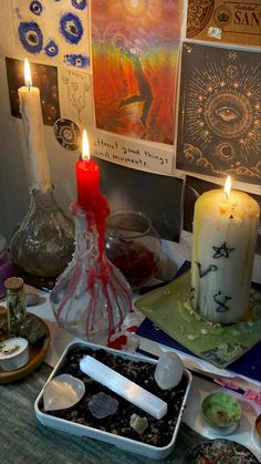 some candles are sitting on a table next to other items and pictures that include artwork