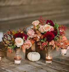 flowers and candles are arranged in vases on a wooden table with pumpkins, succulents and roses