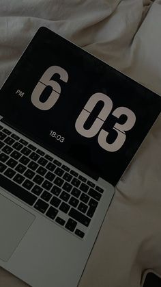 an open laptop computer sitting on top of a bed next to a white mouse and keyboard