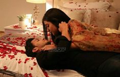 two people laying on a bed with rose petals