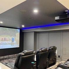 a home theater with black leather chairs and a projector screen in the middle of the room