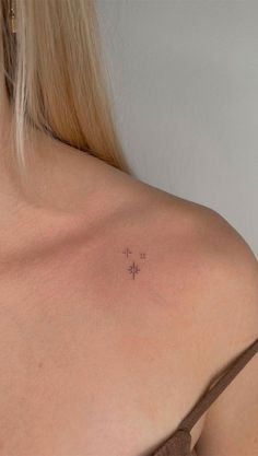 the back of a woman's shoulder with a small star tattoo on her left shoulder