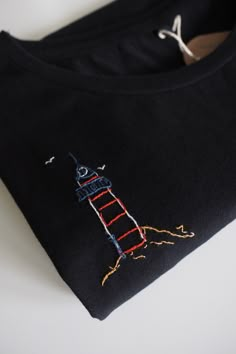 a black t - shirt with a drawing of a lighthouse on it