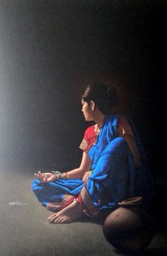 a woman sitting on the ground in a dark room with light coming from behind her