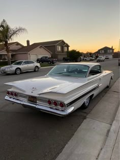 an old car is parked on the side of the road in front of some houses