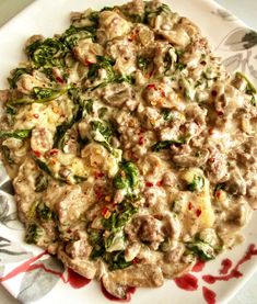 a white plate topped with meat and veggies covered in gravy next to a fork