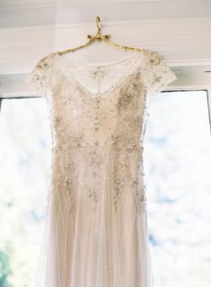 a wedding dress hanging in front of a window