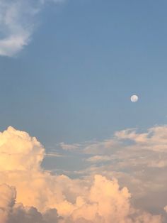 an airplane is flying high in the sky with clouds around it and a half moon