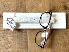 a pair of black glasses sitting on top of a wooden table next to a name tag