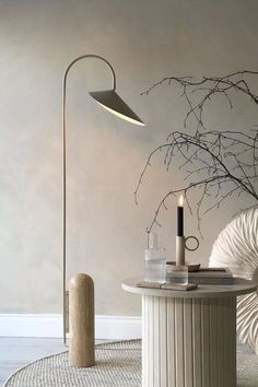 a table with a lamp, candle and vase on it in front of a wall