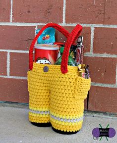 a yellow crocheted bag sitting on the sidewalk next to a red brick wall