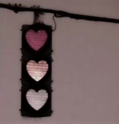 a traffic light with hearts on it hanging from a wire in front of a wall