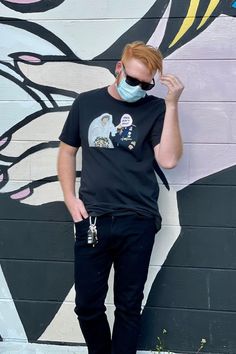 a man wearing a face mask standing in front of a wall