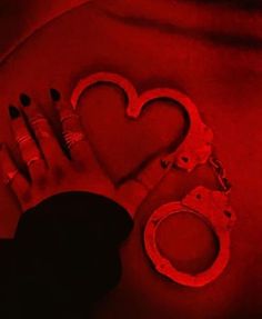 a pair of handcuffs, ring and lipstick on a red background with the shape of a heart