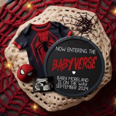 a spiderman shirt and some other items on top of a lace doily with the words, now entering the babyverse