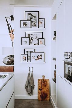 a white kitchen with black and white pictures on the wall