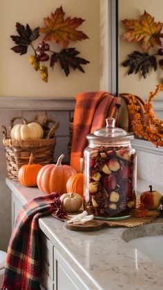 a kitchen counter topped with jars filled with food next to pumpkins and gourds