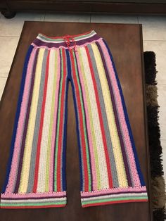 a pair of colorful knitted pants sitting on top of a wooden table next to a rug