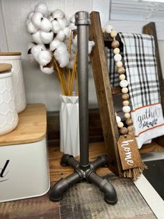 a wooden sign sitting on top of a table next to a vase filled with cotton