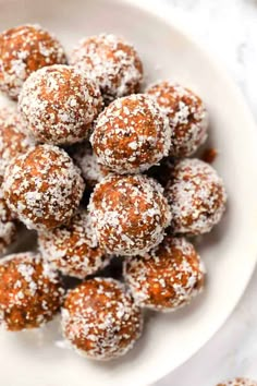 a white bowl filled with powdered sugar covered donuts