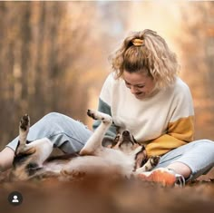 a woman is playing with her dog in the woods