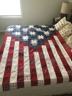 an american flag quilt on a bed in a room with two lamps and a window