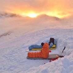 two people laying in the snow with skis on their feet and one person sleeping