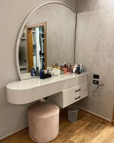 a white vanity with a mirror and stool in front of it on a hard wood floor