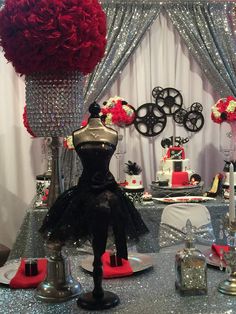 a silver table topped with lots of red flowers and cake stands covered in sequins