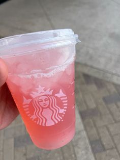 a person holding up a pink drink in their hand