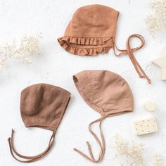 three baby hats and accessories laid out on a white surface