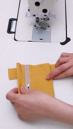 someone is using a sewing machine to sew something on a piece of yellow fabric