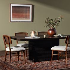 a dining room table with four chairs and a vase on top of it in front of a painting