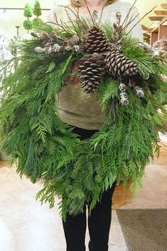 a person holding a plant with pine cones on it's head and wearing black leggings