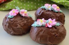 three chocolate covered donuts with flowers on them