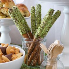 there are many different types of snacks in the glass vases on the table, including pretzels and cookies