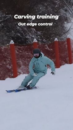 a man riding skis down the side of a snow covered slope next to a red fence