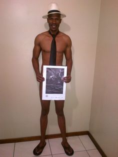 a shirtless man in a hat and tie holding a poster with an image on it