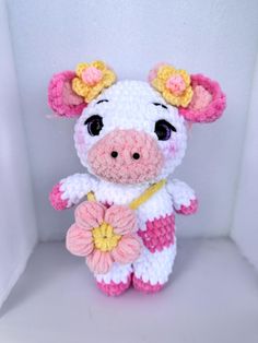 a crocheted stuffed cow holding a flower