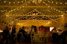 a group of people sitting at tables in a room with lights strung over the ceiling