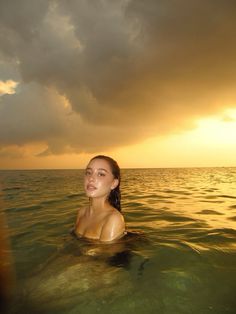 a woman swimming in the ocean at sunset