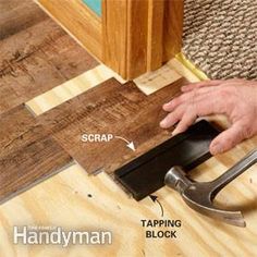 a person using a hammer to cut up wood planks on the floor with tape