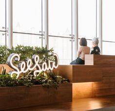 two women sitting on the stairs in front of a sign that says seussa