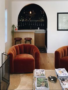 a living room filled with furniture and a bar in the back drop off wall behind it