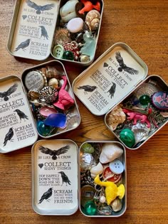 four tins filled with assorted items on top of a wooden table next to each other