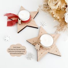 two wooden stars with candles on them next to some flowers and snowflakes in the background